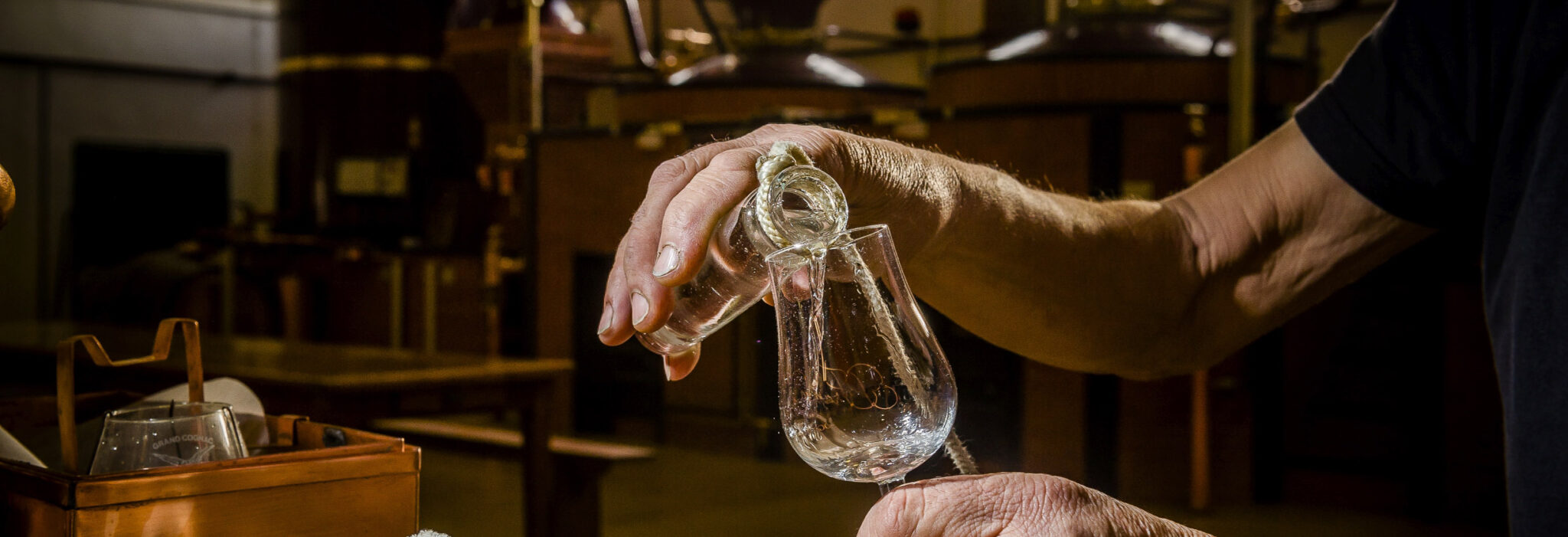 Démonstration de distillation de cognac Personne versant du cognac dans un verre à l'aide d'un alambic en cuivre.