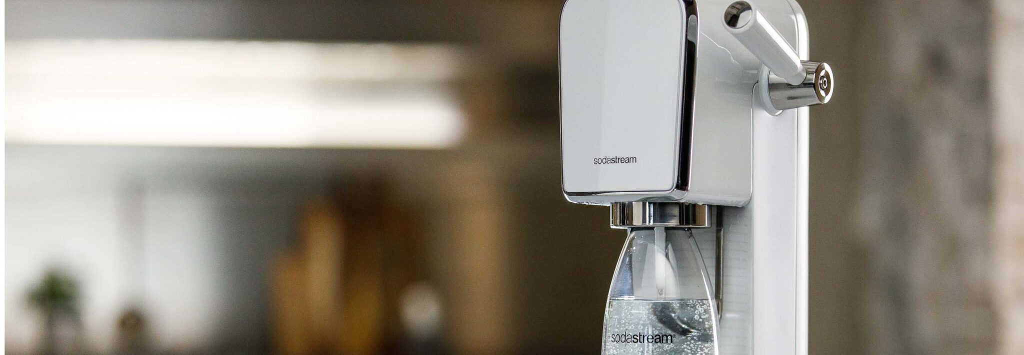 Machine Sodastream en train de gazéifier une bouteille d'eau.