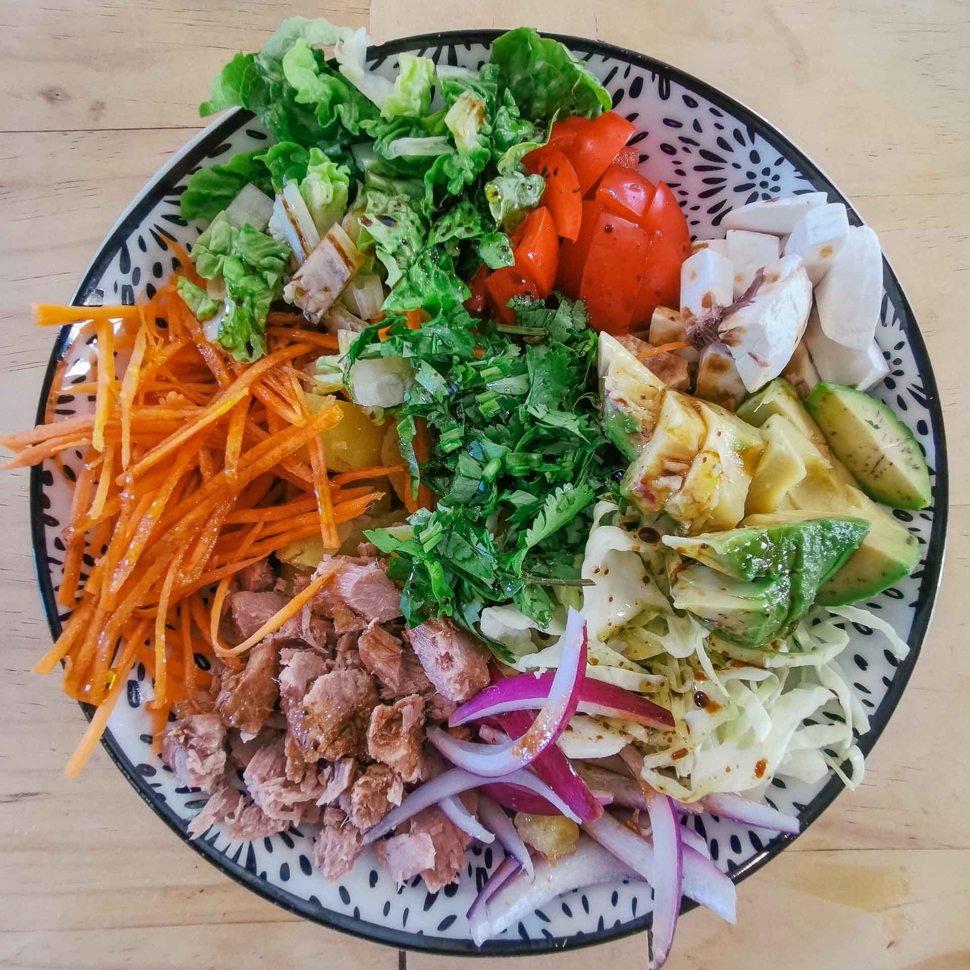Salade colorée avec thon, légumes frais et crudités dans un bol.