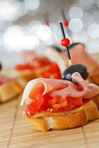 Tartine apéritif avec jambon, tomates, olives et piques décoratives.